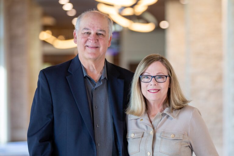 Professional portrait of Dale and Nancy Lockamy, owners of HomeTeam of DFW, smiling together in a brightly lit indoor setting.