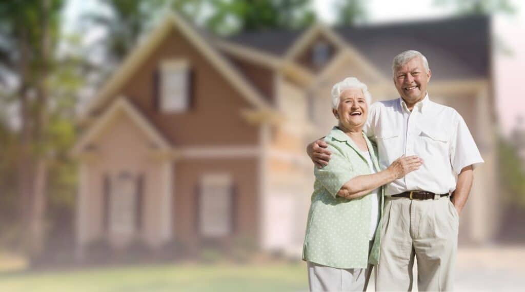 A happy senior couple embracing outdoors in front of their suburban home.
