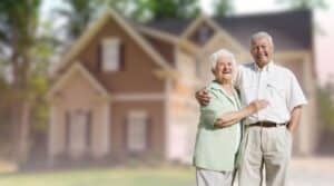 A happy senior couple embracing outdoors in front of their suburban home.