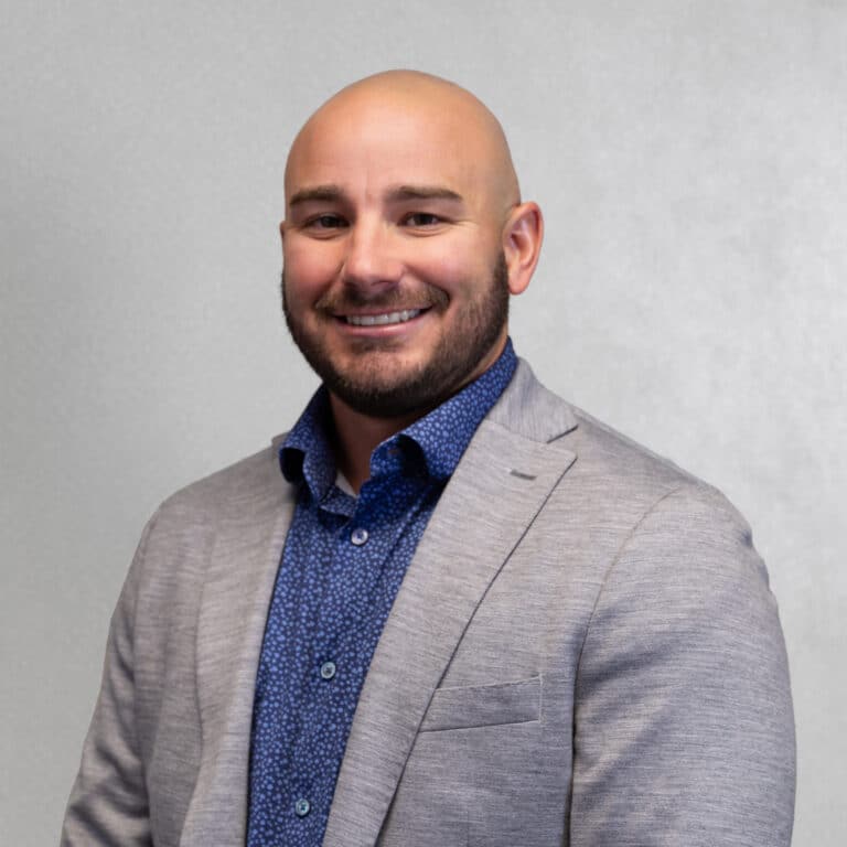 Professional portrait of Austin Klein smiling in a brightly lit indoor setting.
