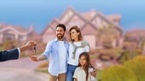Real estate agent handing house keys to a smiling family standing in front of a suburban home.