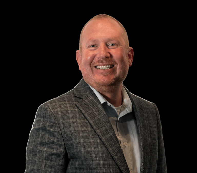 Professional headshot of a man wearing a plaid suit jacket against a black background.